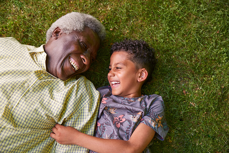 Grandfather Playing With Grandchild in Grass